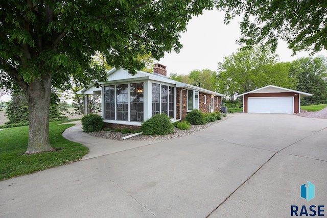 48224 266th St, Brandon, SD 57005 - view of front of home with a sunroom, a detached garage, a chimney, an outbuilding, and brick siding