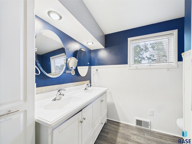 105 S Elm St, Lennox, SD 57039 - bathroom featuring wainscoting, double vanity, toilet, and wood finished floors