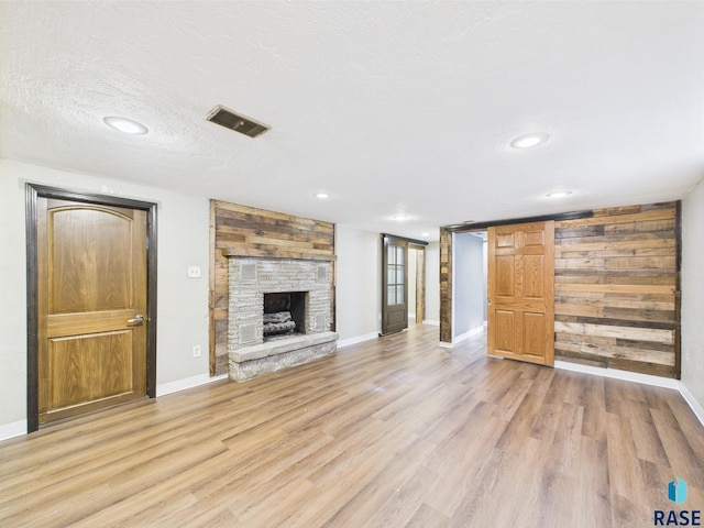 105 S Elm St, Lennox, SD 57039 - unfurnished living room featuring light wood finished floors, a stone fireplace, baseboards, recessed lighting, and a textured ceiling