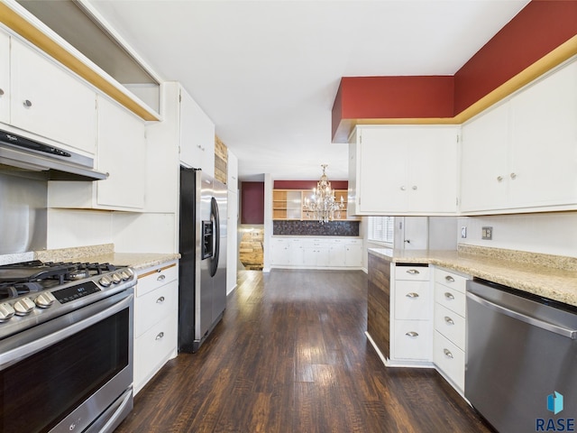 105 S Elm St, Lennox, SD 57039 - kitchen featuring appliances with stainless steel finishes, dark wood-style flooring, a chandelier, under cabinet range hood, and white cabinets