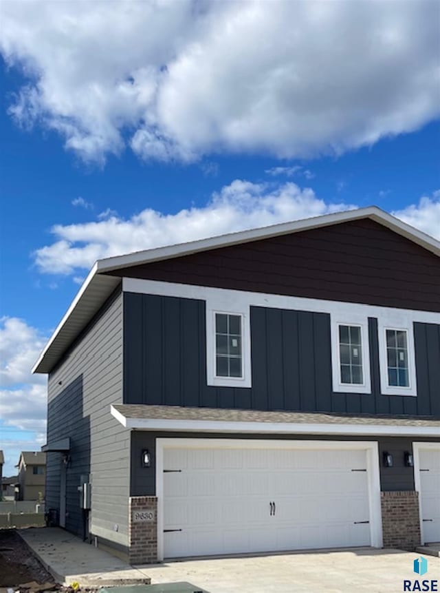 9630 W Tunis Dr, Sioux Falls, SD 57106 - view of side of home with brick siding, a garage, board and batten siding, and concrete driveway