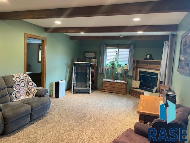218 S Douglas St, Inwood, IA 51240 - carpeted living area featuring a glass covered fireplace, beamed ceiling, and recessed lighting