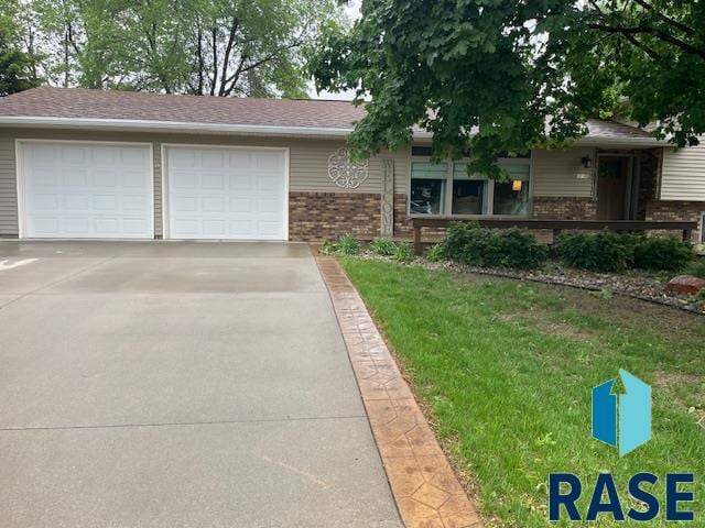 218 S Douglas St, Inwood, IA 51240 - view of front of house featuring brick siding, a front yard, an attached garage, and driveway