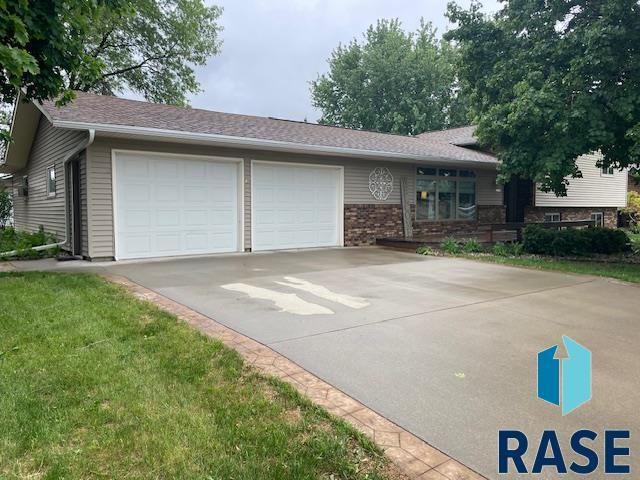 218 S Douglas St, Inwood, IA 51240 - view of front of home featuring a garage, concrete driveway, and brick siding