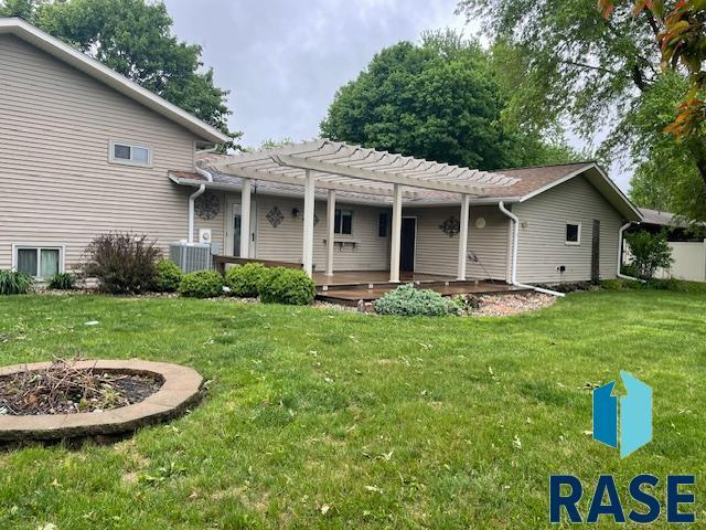 218 S Douglas St, Inwood, IA 51240 - view of front of house featuring a pergola, a front lawn, central air condition unit, a fire pit, and a wooden deck