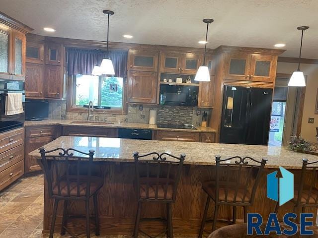 218 S Douglas St, Inwood, IA 51240 - kitchen featuring black appliances, a sink, decorative backsplash, light stone counters, and glass insert cabinets
