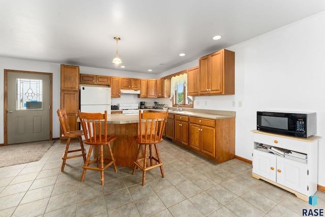 39240 210th St, Huron, SD 57350 - kitchen with black microwave, freestanding refrigerator, brown cabinetry, light countertops, and a kitchen breakfast bar