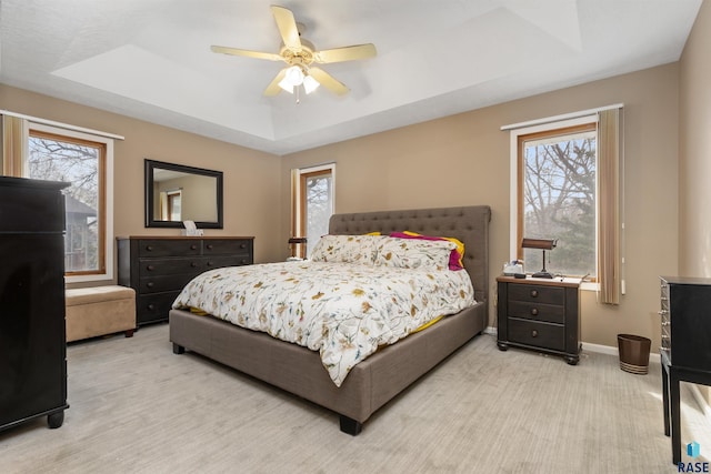 7005 W Strabane Trl, Sioux Falls, SD 57106 - bedroom featuring a tray ceiling, multiple windows, baseboards, and light carpet