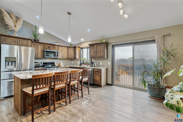 1716 E Tracy Ln, Sioux Falls, SD 57103 - kitchen with stainless steel appliances, vaulted ceiling, light wood-style flooring, a center island, and pendant lighting