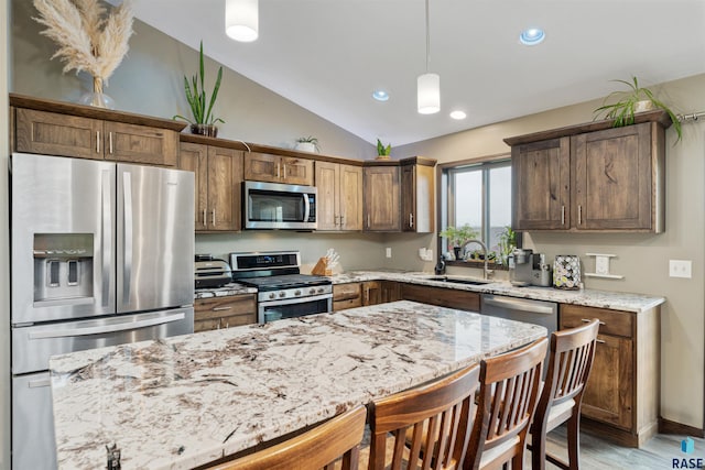 1716 E Tracy Ln, Sioux Falls, SD 57103 - kitchen featuring appliances with stainless steel finishes, a sink, a kitchen bar, lofted ceiling, and light stone countertops