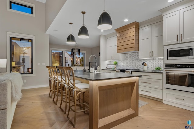 212 Autumnwood Ct, Sioux Falls, SD 57110 - kitchen featuring oven, built in microwave, dark countertops, a breakfast bar area, and a kitchen island with sink