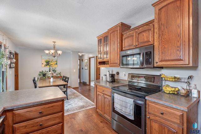 4201 E 22nd St, Sioux Falls, SD 57103 - kitchen with stainless steel appliances, brown cabinetry, dark wood finished floors, a chandelier, and a textured ceiling