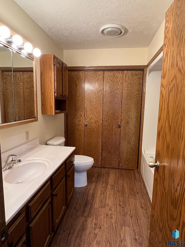 502 E 4th St, Canton, SD 57013 - full bath featuring vanity, wood finished floors, a textured ceiling, toilet, and a tub to relax in
