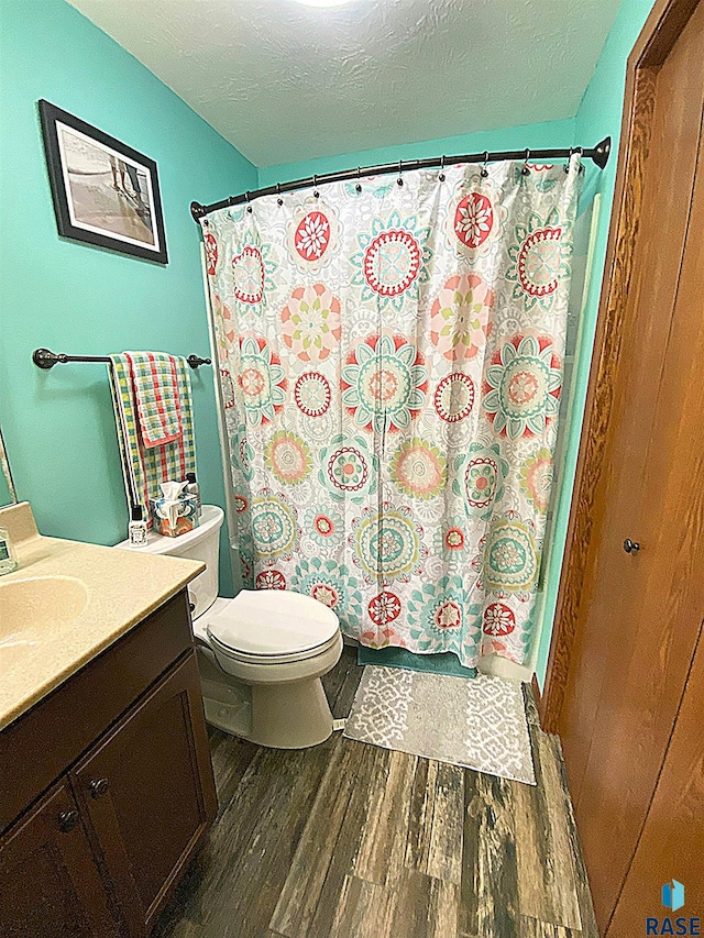 4604 S Woodwind Ln, Sioux Falls, SD 57103 - bathroom with wood finished floors, vanity, toilet, a textured ceiling, and a shower with shower curtain