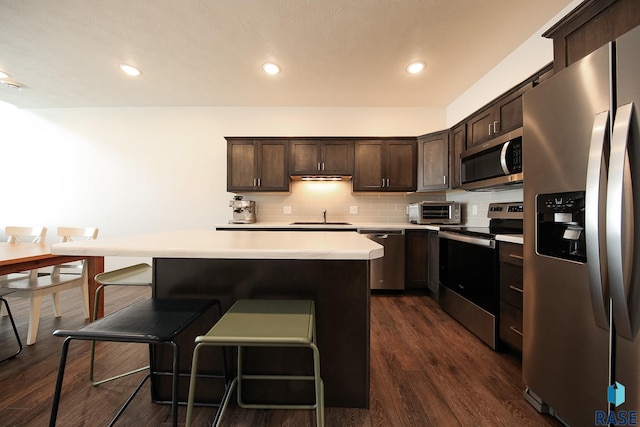 2407 E Copalis Pl, Sioux Falls, SD 57108 - kitchen featuring appliances with stainless steel finishes, light countertops, dark brown cabinets, a sink, and a kitchen bar