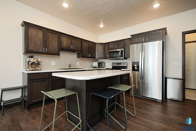 2407 E Copalis Pl, Sioux Falls, SD 57108 - kitchen featuring appliances with stainless steel finishes, a sink, dark brown cabinets, a kitchen breakfast bar, and light countertops