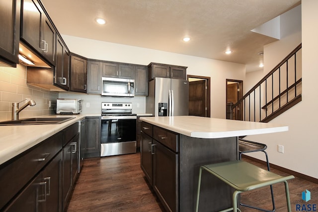 2407 E Copalis Pl, Sioux Falls, SD 57108 - kitchen with appliances with stainless steel finishes, a sink, a kitchen bar, light countertops, and decorative backsplash