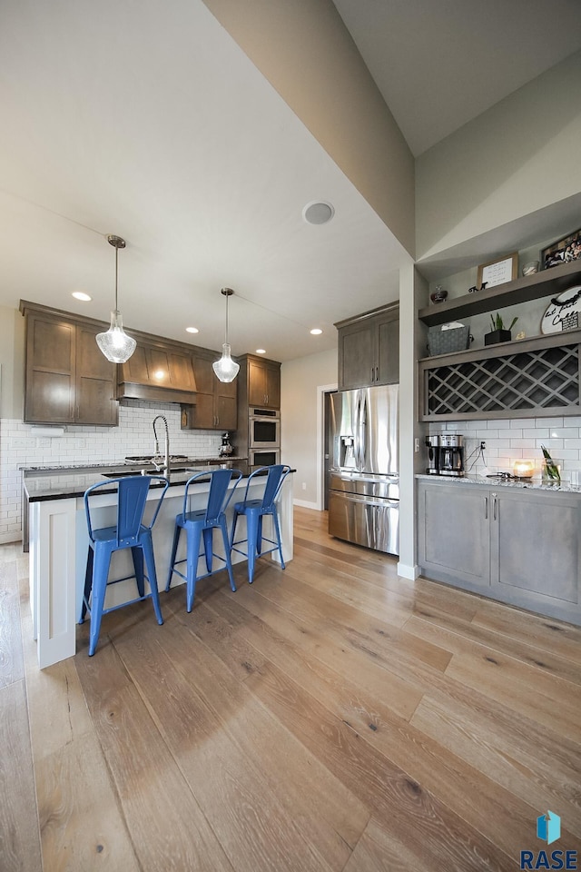 8609 E Fiddlewood Dr, Sioux Falls, SD 57110 - kitchen with stainless steel fridge, decorative backsplash, a kitchen breakfast bar, premium range hood, and recessed lighting