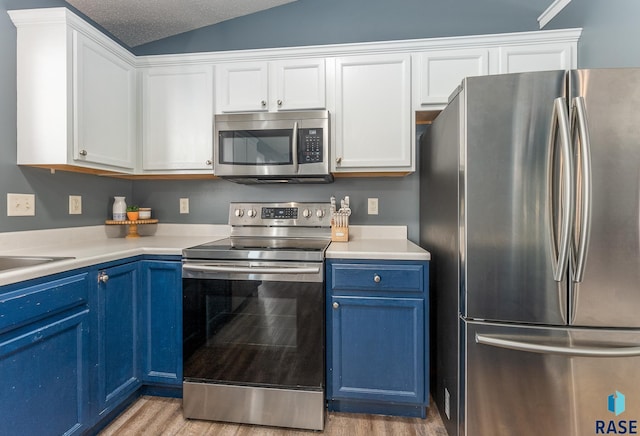 7104 W 68th St, Sioux Falls, SD 57106 - kitchen featuring stainless steel appliances, blue cabinetry, light wood-style flooring, white cabinetry, and vaulted ceiling