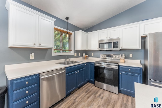 7104 W 68th St, Sioux Falls, SD 57106 - kitchen with stainless steel appliances, blue cabinets, a sink, lofted ceiling, and white cabinets