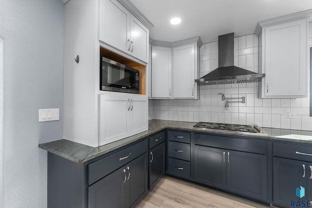 25280 480th Ave, Garretson, SD 57030 - kitchen featuring wall chimney range hood, stainless steel appliances, light wood-style floors, tasteful backsplash, and white cabinetry
