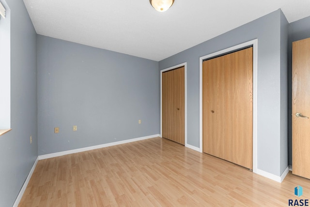 25280 480th Ave, Garretson, SD 57030 - unfurnished bedroom with multiple closets, light wood finished floors, and baseboards