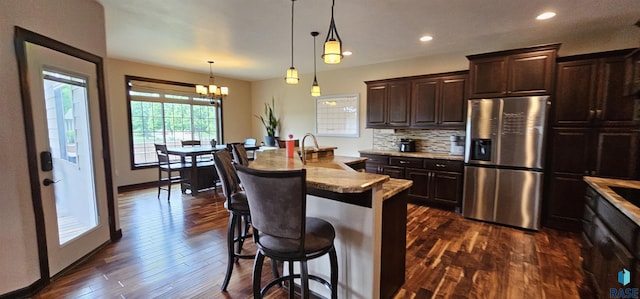 2813 W Stratton Cir, Sioux Falls, SD 57108 - kitchen with stainless steel refrigerator with ice dispenser, a breakfast bar, dark brown cabinets, a chandelier, and dark wood-style floors