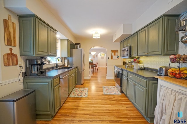 2208 W 22nd St, Sioux Falls, SD 57105 - kitchen featuring arched walkways, green cabinets, a sink, appliances with stainless steel finishes, and light wood-type flooring