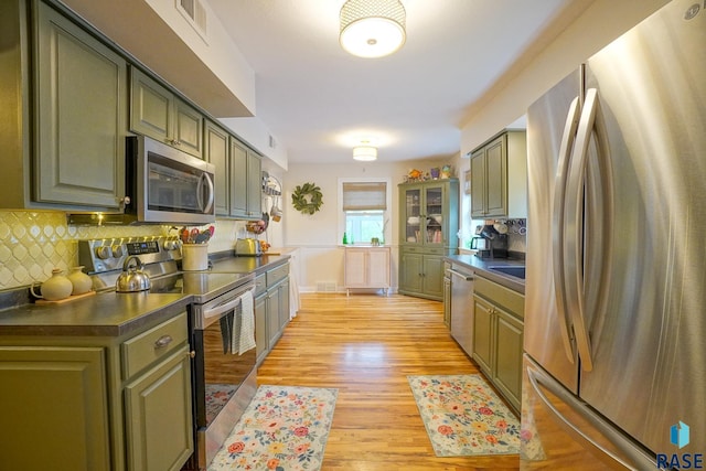 2208 W 22nd St, Sioux Falls, SD 57105 - kitchen with appliances with stainless steel finishes, dark countertops, light wood-style floors, backsplash, and green cabinets