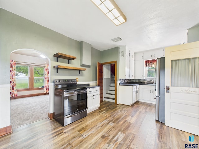 45390 284th St, Hurley, SD 57036 - kitchen featuring stainless steel appliances, light wood finished floors, dark countertops, arched walkways, and white cabinetry