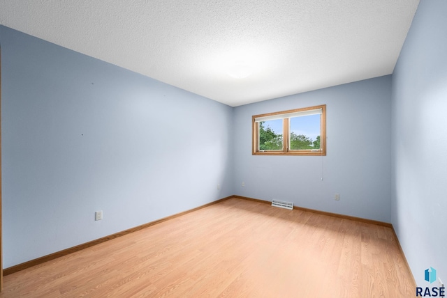 4704 S Pasque Cir, Sioux Falls, SD 57105 - unfurnished room with light wood finished floors, baseboards, and a textured ceiling