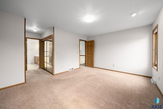 4704 S Pasque Cir, Sioux Falls, SD 57105 - unfurnished bedroom featuring carpet, baseboards, ensuite bathroom, a textured ceiling, and a baseboard radiator