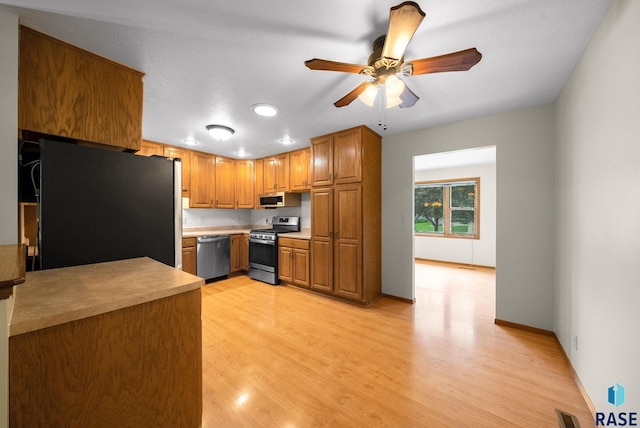 909 E 64th St, Sioux Falls, SD 57108 - kitchen with appliances with stainless steel finishes, light wood-style flooring, brown cabinets, ceiling fan, and light countertops