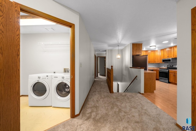 909 E 64th St, Sioux Falls, SD 57108 - laundry room featuring washing machine and dryer, light carpet, baseboards, and light wood-style flooring