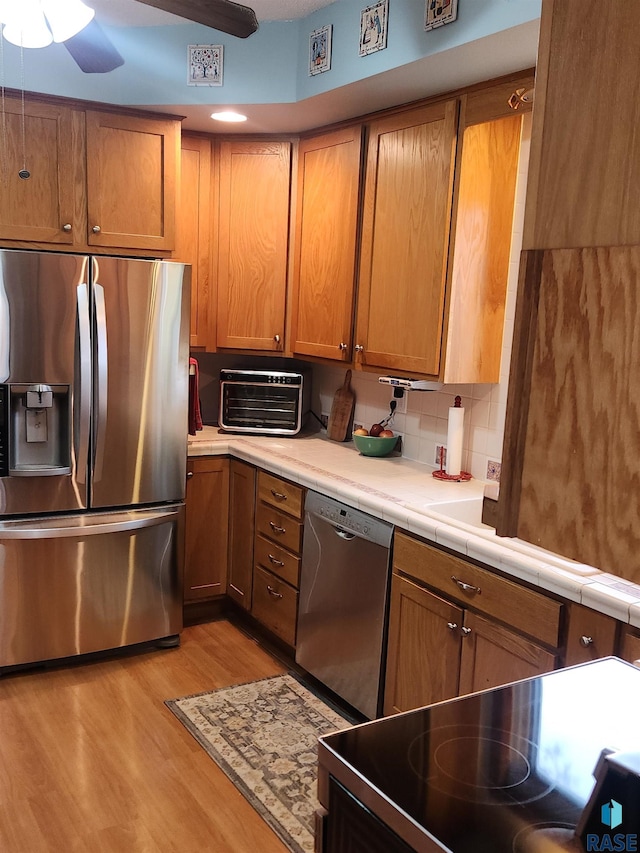 787 70th Ave, Beaver Creek, MN 56116 - kitchen featuring appliances with stainless steel finishes, a ceiling fan, light wood finished floors, brown cabinets, and decorative backsplash