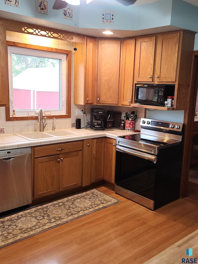 787 70th Ave, Beaver Creek, MN 56116 - kitchen featuring appliances with stainless steel finishes, a sink, tile countertops, tasteful backsplash, and light wood finished floors