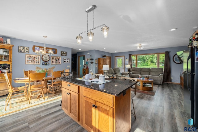 48484 262nd St, Valley Springs, SD 57068 - kitchen featuring a kitchen island, wood finished floors, a chandelier, decorative light fixtures, and dark stone countertops