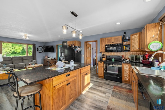48484 262nd St, Valley Springs, SD 57068 - kitchen with black appliances, a sink, light wood-style floors, open floor plan, and a kitchen bar