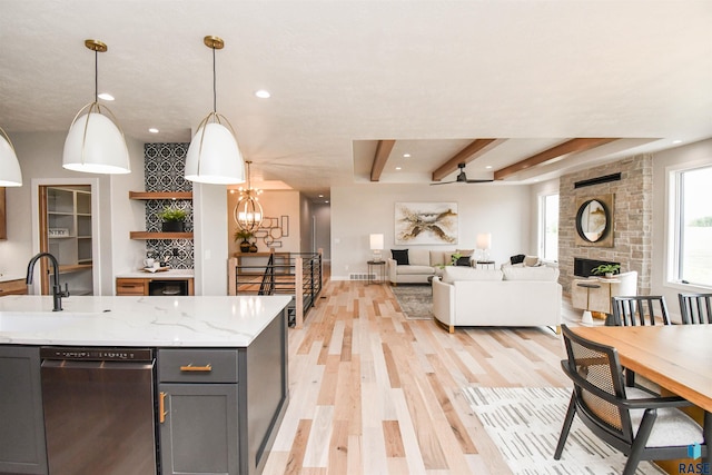 6504 E Hawker Trl, Sioux Falls, SD 57110 - kitchen with stainless steel dishwasher, gray cabinets, light wood finished floors, open floor plan, and a fireplace
