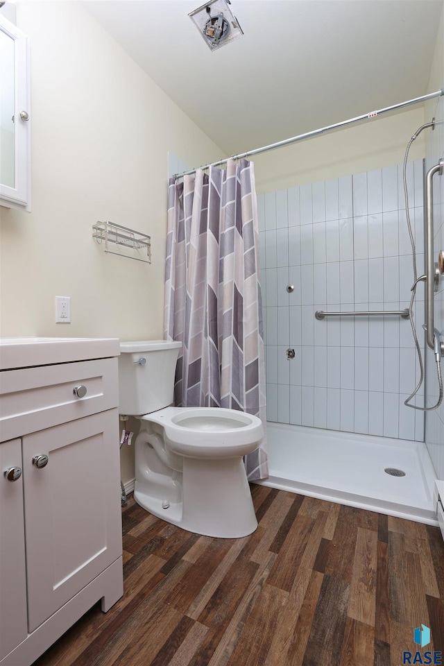 6905 W 6th St, Sioux Falls, SD 57107 - bathroom with wood finished floors, toilet, tiled shower, and vanity