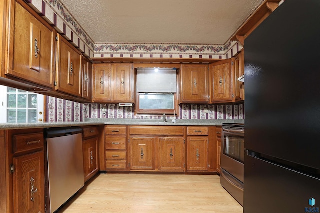 6905 W 6th St, Sioux Falls, SD 57107 - kitchen featuring stainless steel appliances, brown cabinets, light wood-style flooring, a textured ceiling, and light countertops