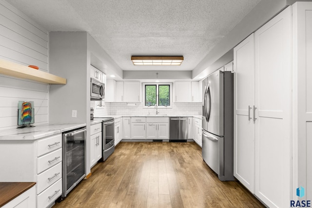 4804 W 39th St, Sioux Falls, SD 57106 - kitchen featuring stainless steel appliances, wine cooler, a textured ceiling, decorative backsplash, and light wood finished floors