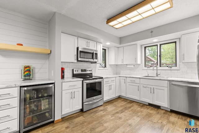 4804 W 39th St, Sioux Falls, SD 57106 - kitchen featuring stainless steel appliances, wine cooler, a sink, white cabinets, and tasteful backsplash