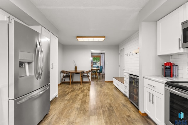 4804 W 39th St, Sioux Falls, SD 57106 - kitchen featuring stainless steel appliances, beverage cooler, white cabinets, light wood-style floors, and backsplash