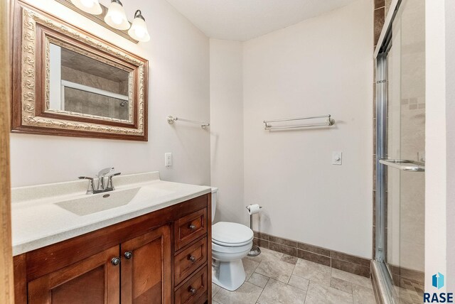 201 N Foss Ave, Sioux Falls, SD 57110 - bathroom featuring vanity, toilet, a shower with door, baseboards, and tile patterned floors