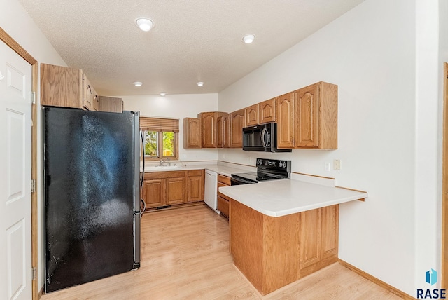 201 N Foss Ave, Sioux Falls, SD 57110 - kitchen with black appliances, a peninsula, a sink, light wood-style floors, and light countertops