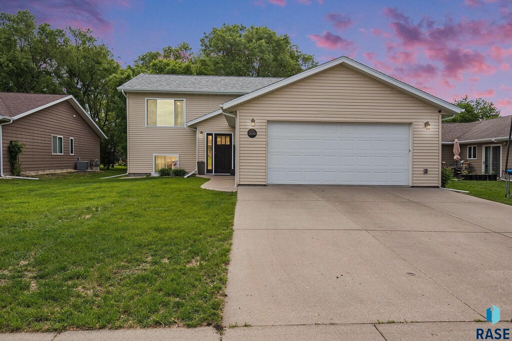 506 Silver Creek Cir, Madison, SD 57042 - view of front of house featuring an attached garage, a front yard, concrete driveway, and cooling unit