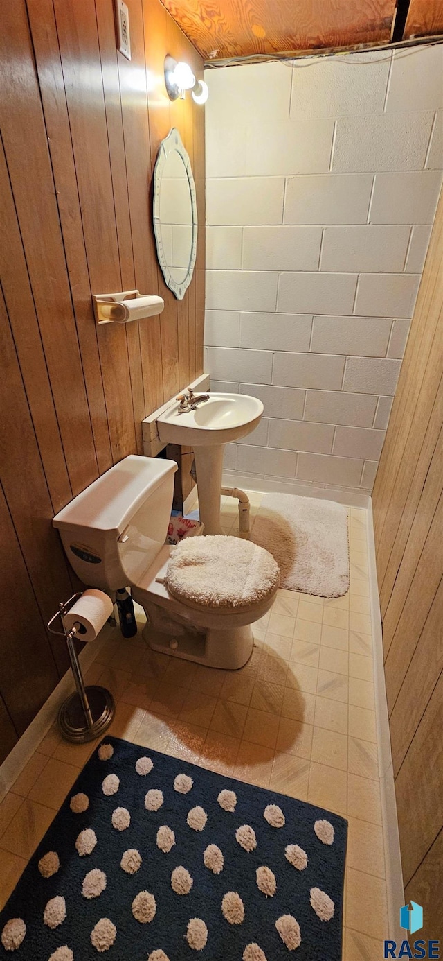 1024 Orchard Dr, Brookings, SD 57006 - bathroom featuring wood walls, toilet, and tile patterned flooring