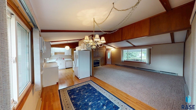1024 Orchard Dr, Brookings, SD 57006 - unfurnished dining area with a chandelier, a sink, a baseboard radiator, light wood finished floors, and a fireplace