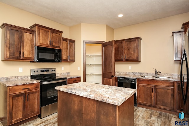 6400 S Keller Cir, Sioux Falls, SD 57108 - kitchen featuring black appliances, a sink, light wood-style floors, a center island, and light stone counters
